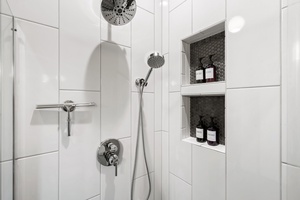 Refresh in a bright, tiled walk-in shower with sleek built-ins for your essentials.