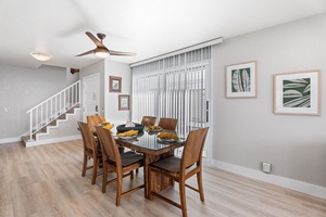 Dining area with seating for six and natural light filtering through vertical blinds.