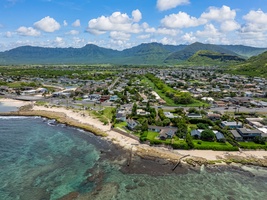 Stunning coastal town aerial view showcasing pristine beaches, turquoise waters, and dramatic mountain backdrop creating a tropical paradise setting.