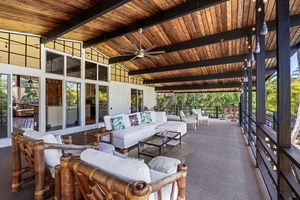 Unwind in your covered terrace with tropical bamboo furnishings, exposed beams, and tropical landscape views creating the perfect outdoor retreat.