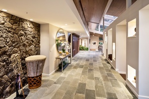 Entry hall with stone floors, gallery lighting, and indoor landscaping creates a resort-style welcome.