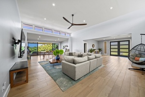 Skylit living area merges comfy sectional, greenery, and wall-height sliders.