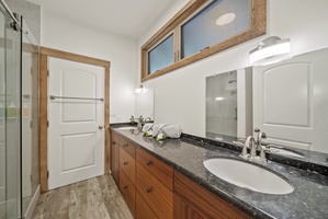 Jack and Jill bathroom with granite vanity, warm wood cabinetry, and bright natural lighting.