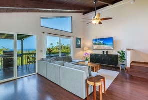 Curl up with friends and family in the bright living area, featuring vaulted ceilings, ample seating, and ocean views through large windows.