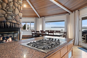 Cook your favorite meals while gazing at breathtaking water views through floor-to-ceiling windows in this stunning open-concept kitchen.
