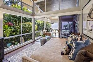 Cozy reading nook and retreat space surrounded by glass and tropical greenery.