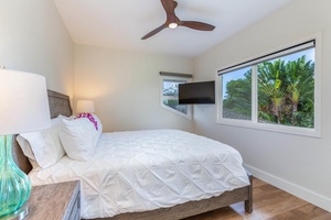 Guest bedroom at Pohaku Villa, complete with flat-screen TV and bright window views.