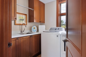 Your personal laundry room features full-size washer and dryer with rich wooden cabinetry and convenient sink for all your washing needs.