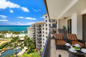 Ocean and beach views from this beachfront property balcony with comfortable seating and tropical landscaping below.