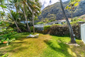 Relax on the chaise lounge amidst a lush grassy expanse, with the luxurious home and majestic mountains framing the perfect backdrop.