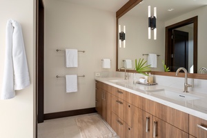 Primary Suite #2: Refresh in your polished bathroom featuring a spacious dual vanity, pristine white towels, and warm wood accents.