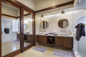 Your spa-like bathroom features dual vanities, elegant round mirrors, and rich wood accents that create a luxurious retreat for your daily rituals.