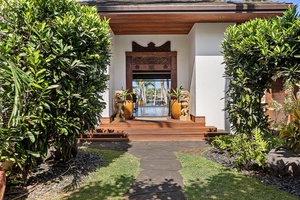 An elegant entrance welcomes guests with carved wooden details, tropical landscaping, and traditional architectural charm.