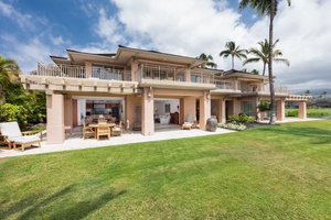 A stunning ocean view villa with expansive lawns and palm trees, featuring elegant architecture and spacious outdoor terraces.