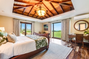 Primary suite with king bed, private lanai access, and peaceful garden and partial ocean views.