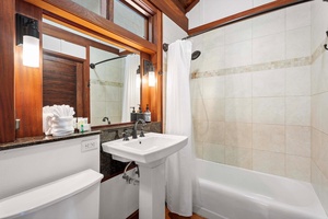 Elegant guest bathroom with a tub, shower, and natural wood details.