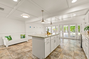 Your bright, airy kitchen and lounge await—marble counters, tropical touches, and sunlight streaming through French doors to the patio.