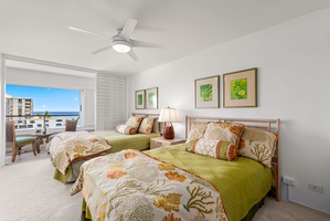 Guest bedroom offers two beds with colorful island linens and ocean glimpses—perfect for friends or kids.