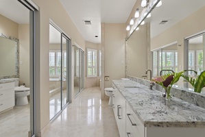 This primary bath includes granite vanities, a spacious dressing area, and luxury finishes for a full spa-at-home experience.