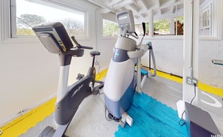 Home gym with exercise bike and elliptical machine.
