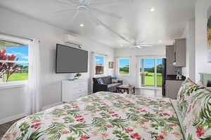 Guest bedroom 1 featuring a tropical theme with floral bedding and expansive windows for a bright, inviting atmosphere.