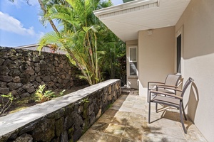 Unwind in your private tropical sanctuary with outdoor seating surrounded by lush palms and authentic stone walls.