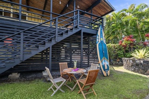 Your private outdoor dining nook awaits beneath the stairs, complete with tropical garden views and a paddle board ready for island adventures.