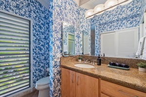 Wailea Ekolu 1106 bathroom includes a wide vanity, chic wallpaper, and plenty of natural light.