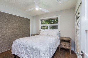 Guest bedroom at Lani Oasis with a cozy queen bed and serene window view for restful nights.