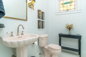 Whimsical half-bath with pedestal sink and stained glass window.