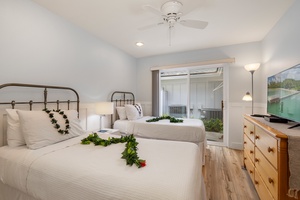 Guest bedroom with two twin beds, calming coastal tones, and direct lanai access.