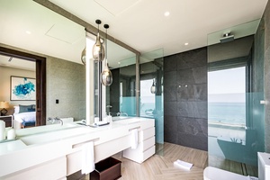 Indulge in the modern ensuite bathroom with a dual vanity, glass-enclosed shower, and breathtaking ocean views.