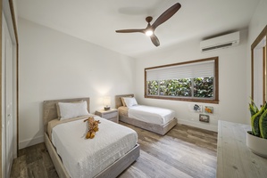Twin guest bedroom with garden views, ceiling fan, and natural light—great for kids or friends.