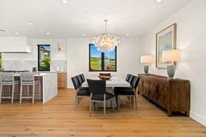 Your open-concept dining space flows seamlessly into the gourmet kitchen, where warm wood floors meet elegant quartz countertops under a stunning glass chandelier.
