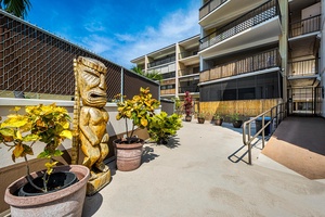 Charming tropical courtyard with decorative tiki statue and lush plants creates a welcoming island atmosphere at this multi-level property.