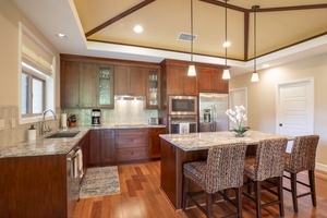 A chef’s dream kitchen awaits, equipped with granite counters, wine fridge, and top-tier appliances.