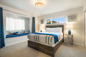 Drift off in your serene bedroom featuring coastal blues, crisp linens, and a cozy window nook perfect for morning coffee.