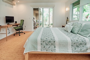 Your bright bedroom combines comfort with productivity, featuring a cozy bed and dedicated workspace overlooking a peaceful garden patio.