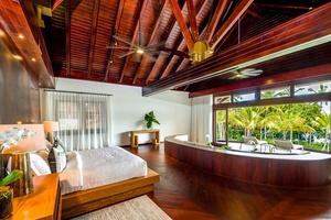 Enjoy the elegance of this spacious bedroom with a curved sofa and garden view, and ample natural light.