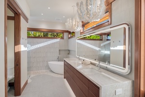 Primary ensuite bathroom with a double vanity, modern lighting, and garden views.