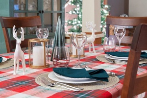 Table adorned with plaid, candles, and reindeer decorations, perfect for a Christmas dinner.