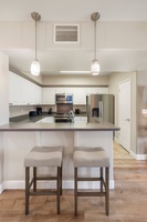 Barstool seating and pendant lighting create a versatile kitchen space—equally ideal for meal prep, laptop time, or morning mimosas.