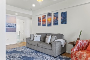 Downstairs living room from another angle, highlighting ample seating and bright natural light flowing in from the shoreline.