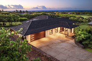 Aerial view of the home's entrance surrounded by lush greenery and a serene ocean backdrop.