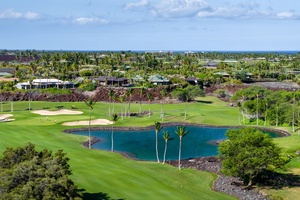 Scenic view of a lush golf course with a tranquil pond, surrounded by tropical greenery.