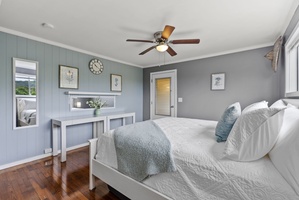 Warm wood floors flow through this serene guest room, offering comfort and style.