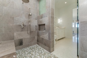 Luxurious walk-in shower with floor-to-ceiling tile and built-in bench seating.