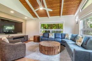 The living area at Lani Oasis offers cozy sectional seating, garden views, and easy access to the poolside lanai.