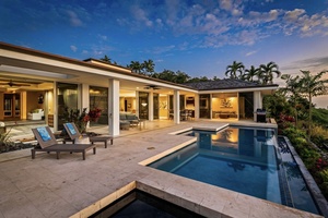 Modern tropical villa showcases seamless indoor-outdoor living with private pool and lush landscaping under dramatic evening skies.