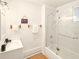 Refresh in your pristine bathroom featuring a refreshing shower, fluffy towels, and charming nautical touches that create a spa-like retreat.
